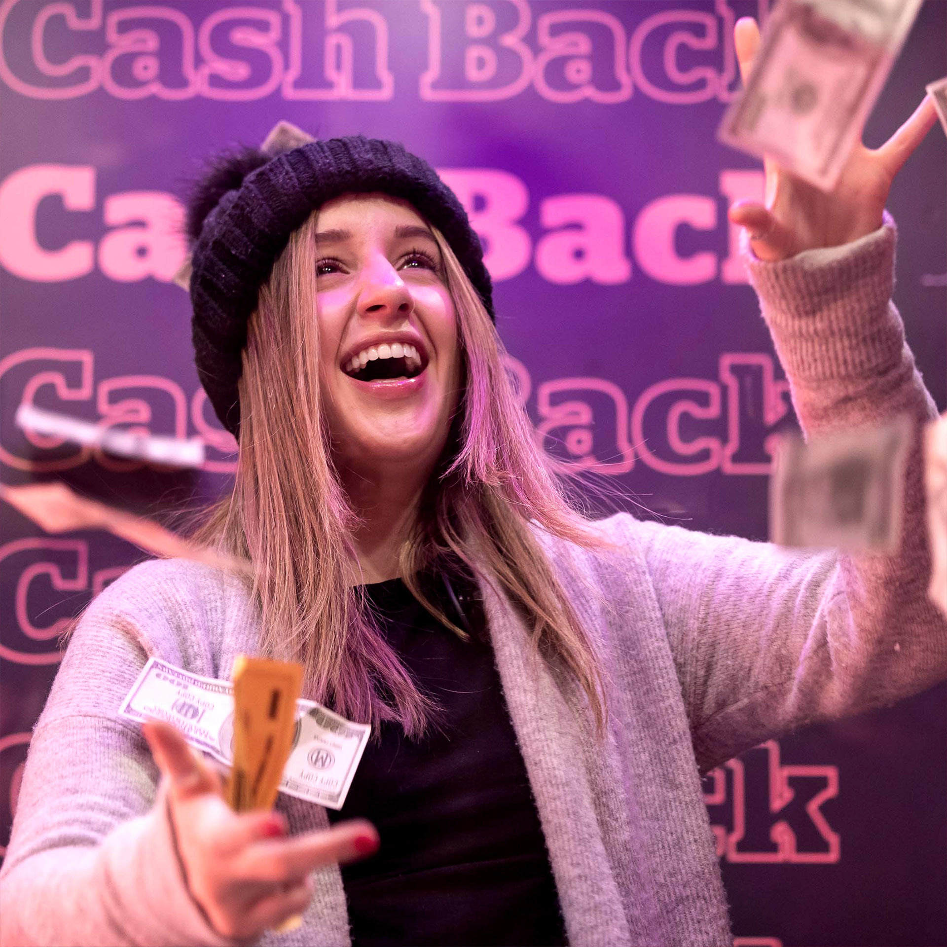 A consumer inside of the money machine holds money in her right hand. 