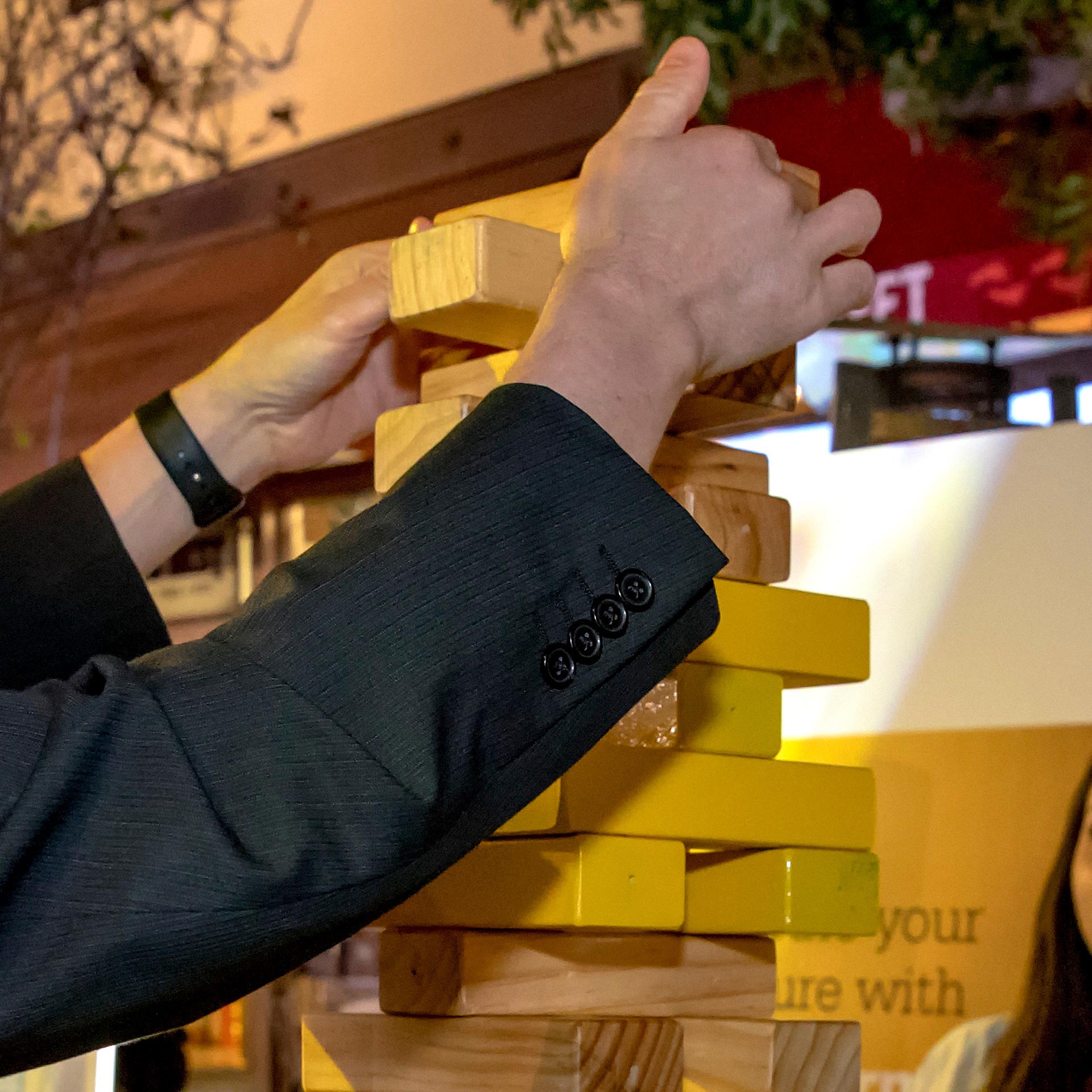 A human hand actively uses wooden blocks to build a tower. 