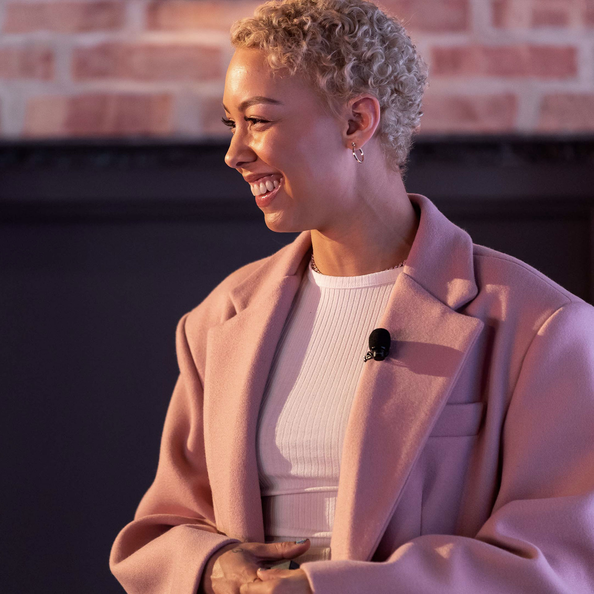 Elise Swopes, an influencer on Instagram, wears a soft pink blazer over a pink shirt. She is smiling and having fun